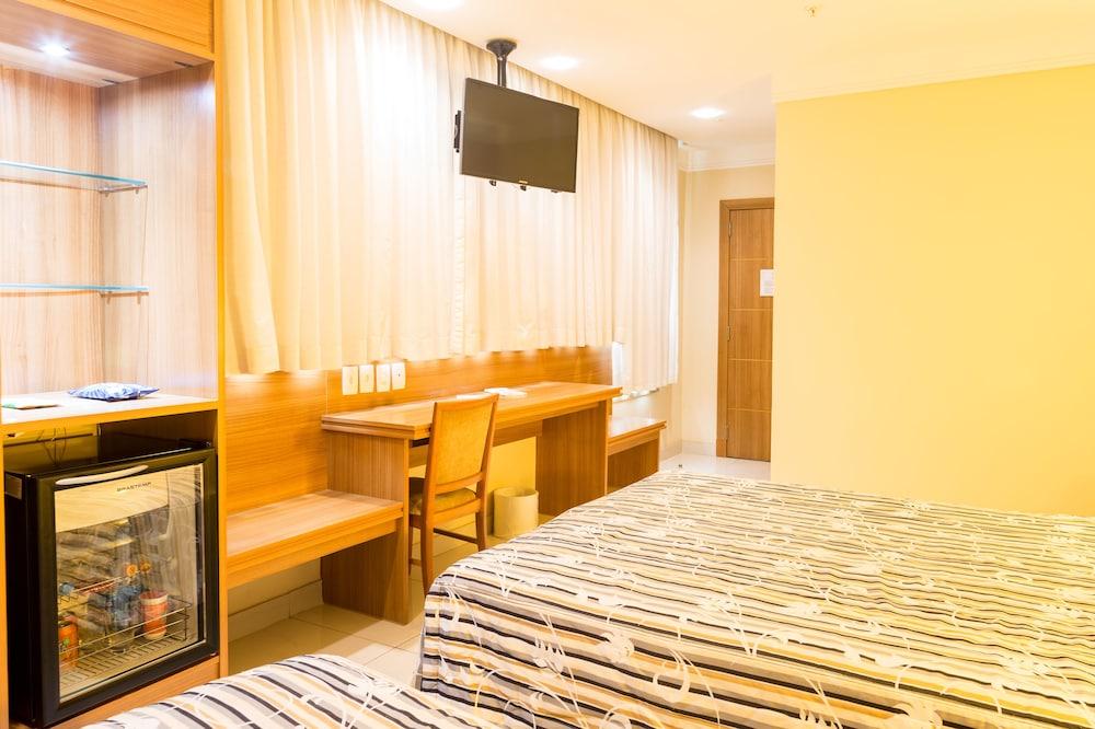 Hotel Atlantico Business Centro Rio de Janeiro Eksteriør bilde The photo shows a hotel room with two beds featuring striped bedding. There is a wooden desk and chair near a window with light-colored curtains. A flat-screen television is mounted on the wall, and there appears to be a small refrigerator or mini-ba